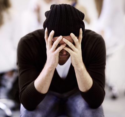 Depressed man covering his face with hands